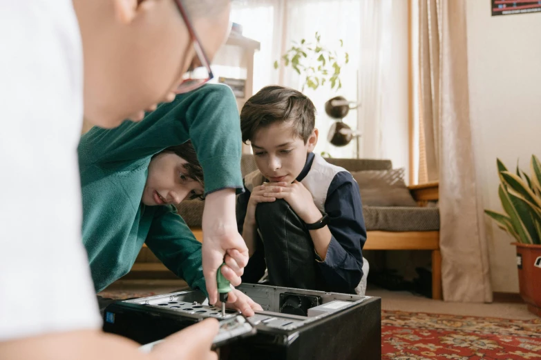 a man and two boys playing a video game, pexels contest winner, visual art, looking at the treasure box, repairing the other one, lachlan bailey, school curriculum expert