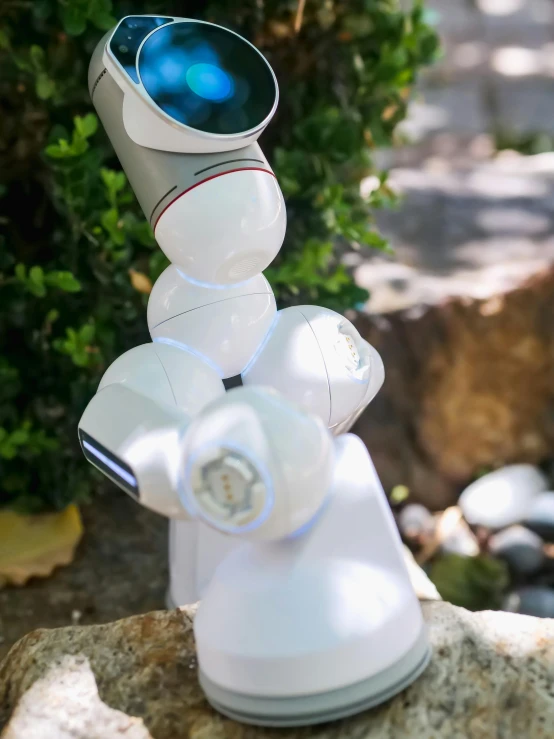 a white robot sitting on top of a rock, in the garden, with anamorphic lenses, healing pods, sassy pose