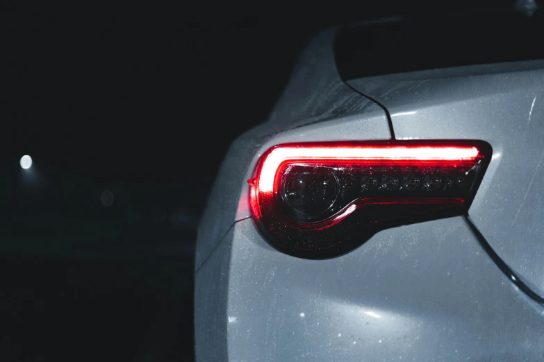 a close up of the tail lights of a car, inspired by Elsa Bleda, pexels contest winner, renaissance, on a gray background, toyota supra, late night, instagram post