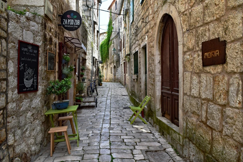 a narrow cobblestone street with tables and chairs, by Matija Jama, pexels contest winner, limestone, square, cottagecore hippie, a wooden