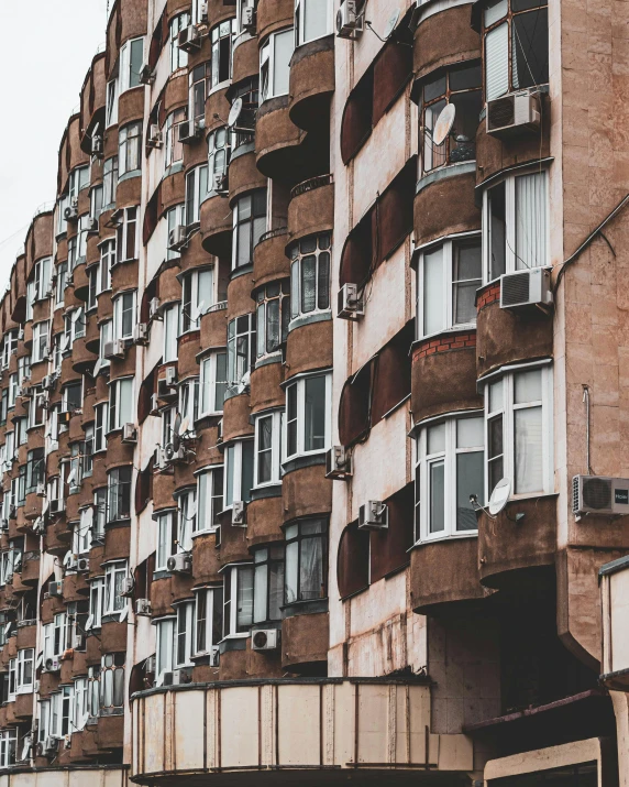 a very tall building with lots of windows, by Emma Andijewska, pexels contest winner, brutalism, soviet apartment buildings, mud and brick houses, rows of doors, crenellated balconies