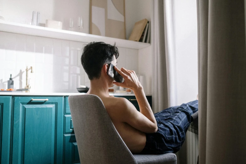 a man sitting in a chair talking on a cell phone, trending on pexels, wearing nothing, his arms are behind his back, young man with short, in the morning