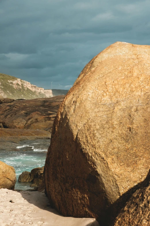 a large rock sitting on top of a sandy beach, unsplash, australian tonalism, tall big rocks, panorama, 4k”