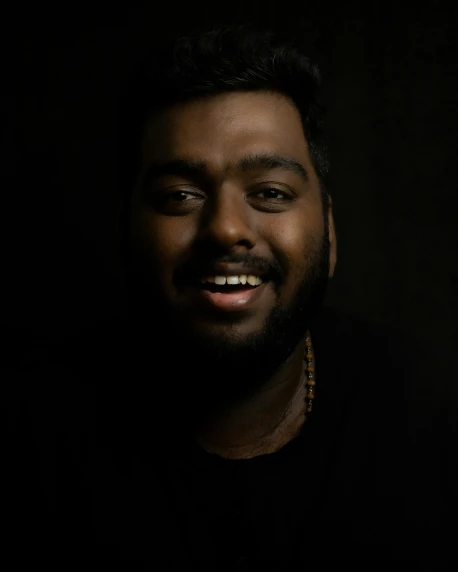 a man with a beard smiles at the camera, an album cover, trending on unsplash, hurufiyya, non-binary, indian, ((portrait)), good lighted photo