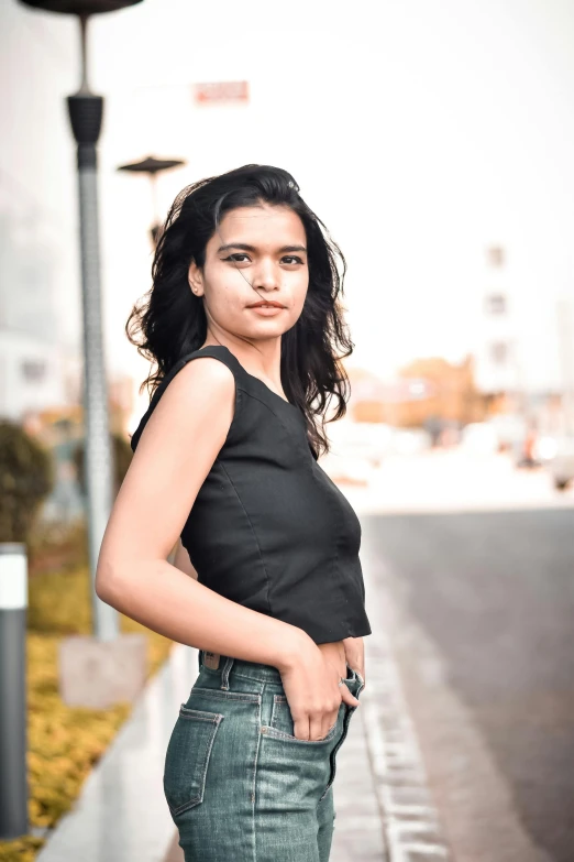 a woman standing on the side of a road, she is wearing a black tank top, indian girl with brown skin, 5 0 0 px models, portrait image