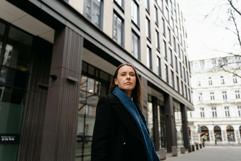 a woman standing in front of a tall building, by Emma Andijewska, looking serious, on the street, in london, emma uber