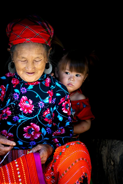 a woman sitting with a child in her lap, by Reuben Tam, pexels contest winner, wearing authentic attire, square, vietnam, screensaver