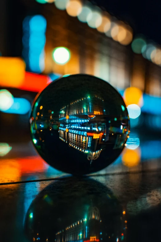 a glass ball sitting on top of a table, a picture, by Chris Rallis, unsplash contest winner, vibrant city lights, refracted, high angle close up shot, in city street at night