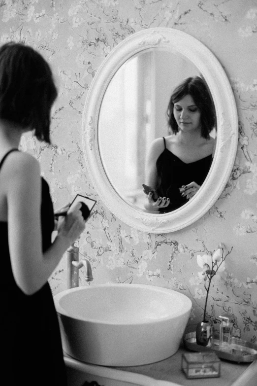 a woman standing in front of a bathroom mirror, a black and white photo, happening, brunette, she is holding a smartphone, lily frank, kaethe butcher