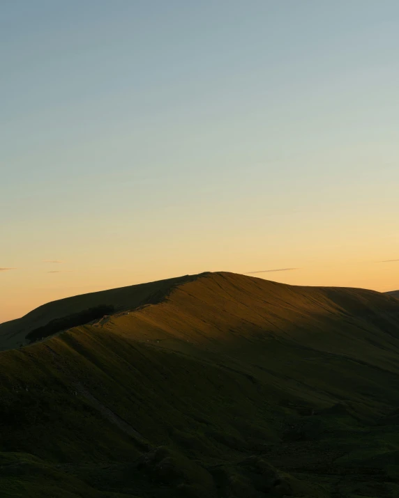 a man flying a kite on top of a lush green hillside, by Peter Churcher, unsplash contest winner, les nabis, evening sunset, wales, crater, seen from a distance