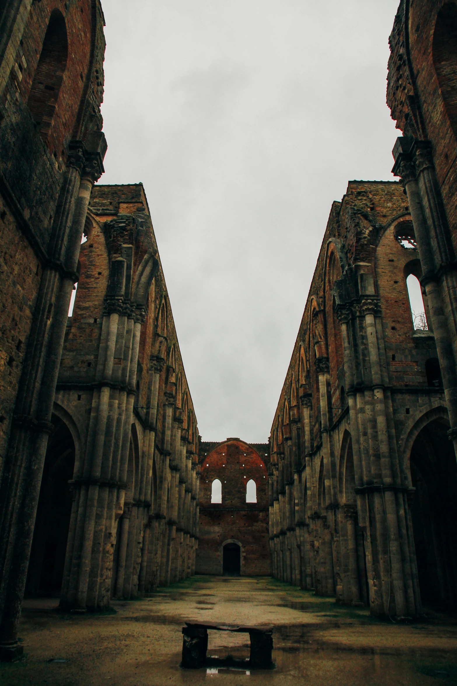 a couple of benches that are in the middle of a building, an album cover, inspired by Taddeo Gaddi, unsplash contest winner, romanesque, huge giant old ruins, dark gloomy church, view from the ground, buttresses