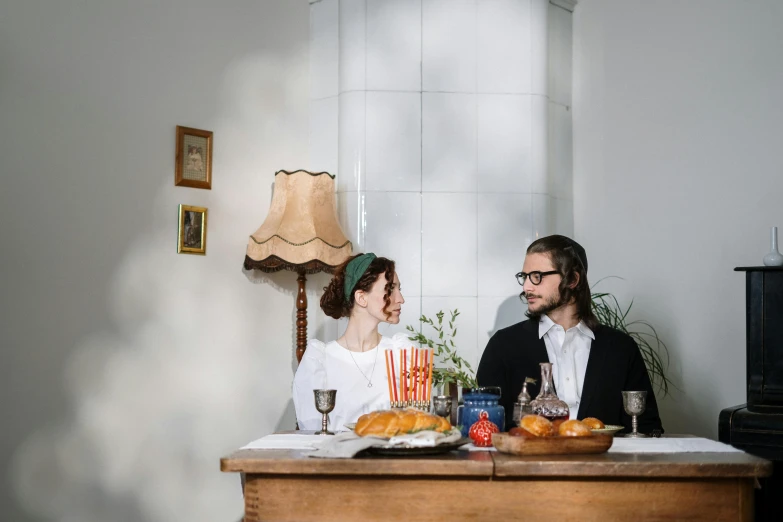 a man and a woman sitting at a table, by Emma Andijewska, unsplash, renaissance, sukkot, on a white table, snacks, vintage inspired