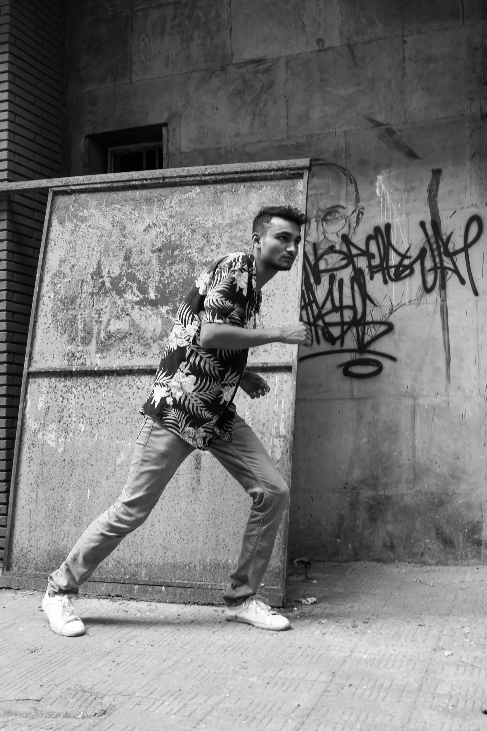 a man walking past a wall with graffiti on it, an album cover, fighting pose, greyscale 1 9 9 0, with hawaiian shirt, photography alexey gurylev