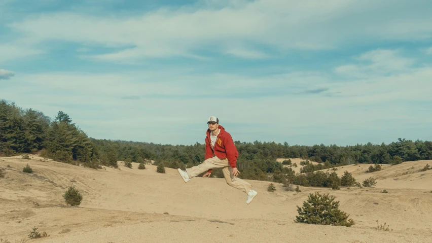 a man that is standing in the sand with a frisbee, inspired by mads berg, pexels contest winner, figuration libre, travis scott flying over earth, wearing red jacket, in avila pinewood, badlands