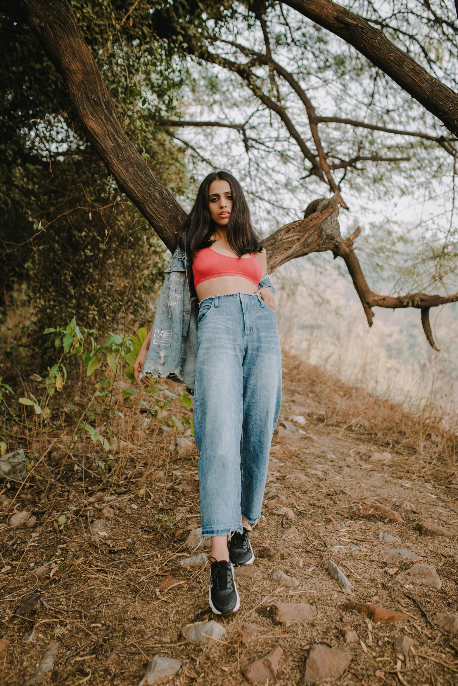 a woman standing on a dirt road next to a tree, baggy jeans, portrait featured on unsplash, croptop, avatar image