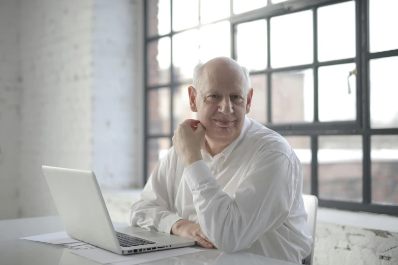 a bald man sitting in front of a laptop computer, pexels contest winner, norman foster, in white room, avatar image, portrait image