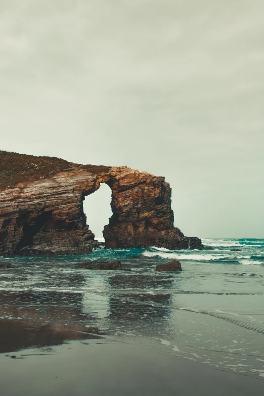 a couple of people standing on top of a sandy beach, rock arches, very aesthetically pleasing, marsden, unsplash 4k