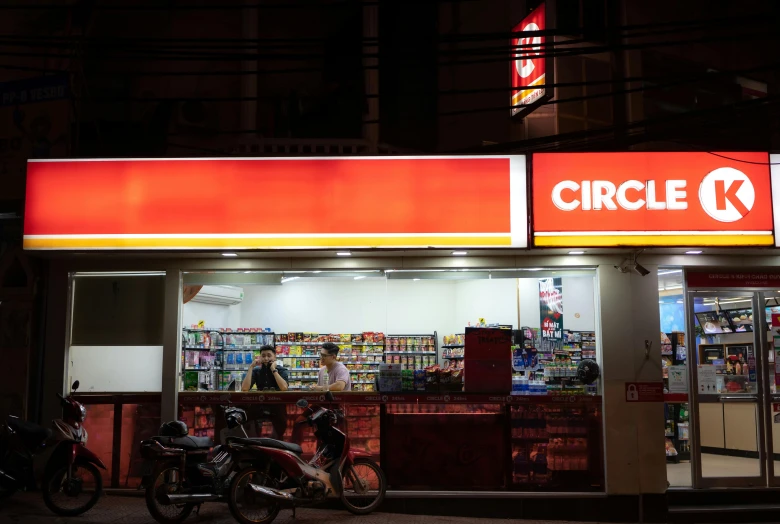 a group of motorcycles parked in front of a circle 6 store, a portrait, by Cricorps Grégoire, futuristic phnom-penh cambodia, welcome to the circus, pharmacy, night photo