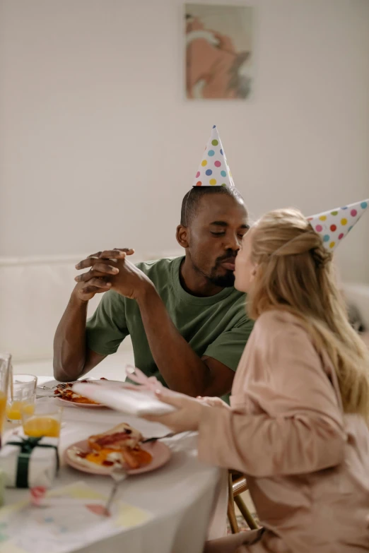 a man and woman sitting at a table eating pizza, pexels contest winner, photorealism, wearing a party hat, making out, mkbhd, at a birthday party