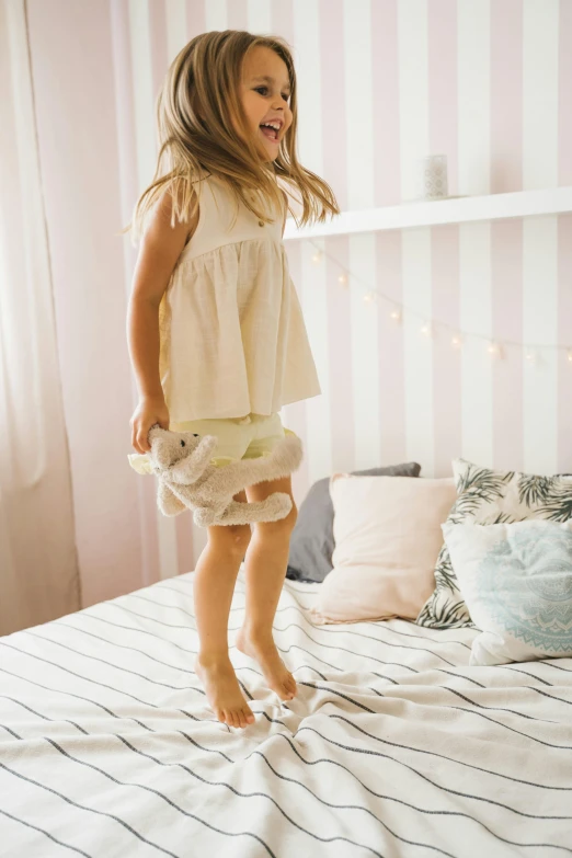 a little girl jumping on top of a bed, inspired by Elsa Beskow, pexels contest winner, soft cute colors, fashionable, beige, young teen