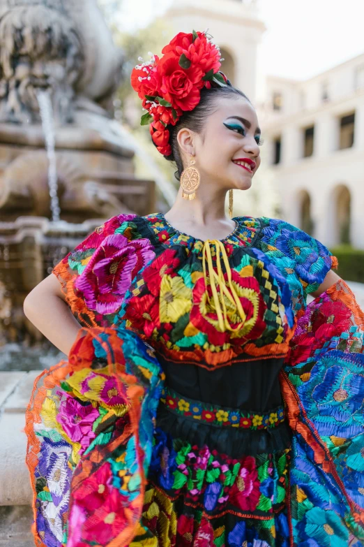 a woman in a colorful dress standing in front of a fountain, inspired by Frida Kahlo, pexels contest winner, renaissance, folklorico, square, jeweled costume, promotional image