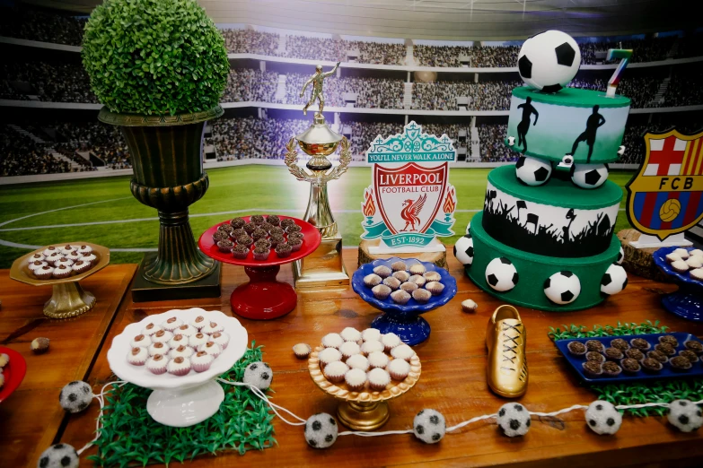 a table topped with lots of food on top of a wooden table, liverpool football club, birthday cake on the ground, cups and balls, slide show