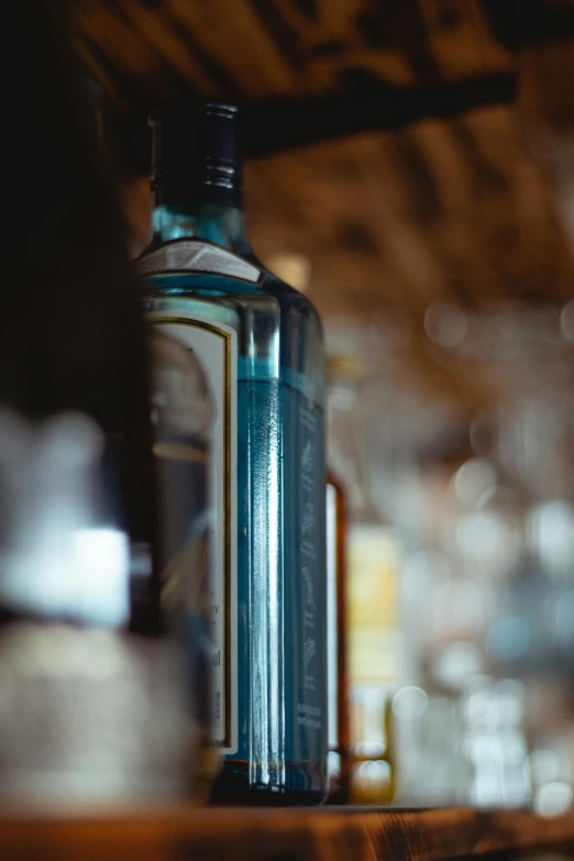 a bottle of alcohol sitting on top of a wooden shelf, a portrait, unsplash, light blues, close-up shot taken from behind, digital image, thumbnail