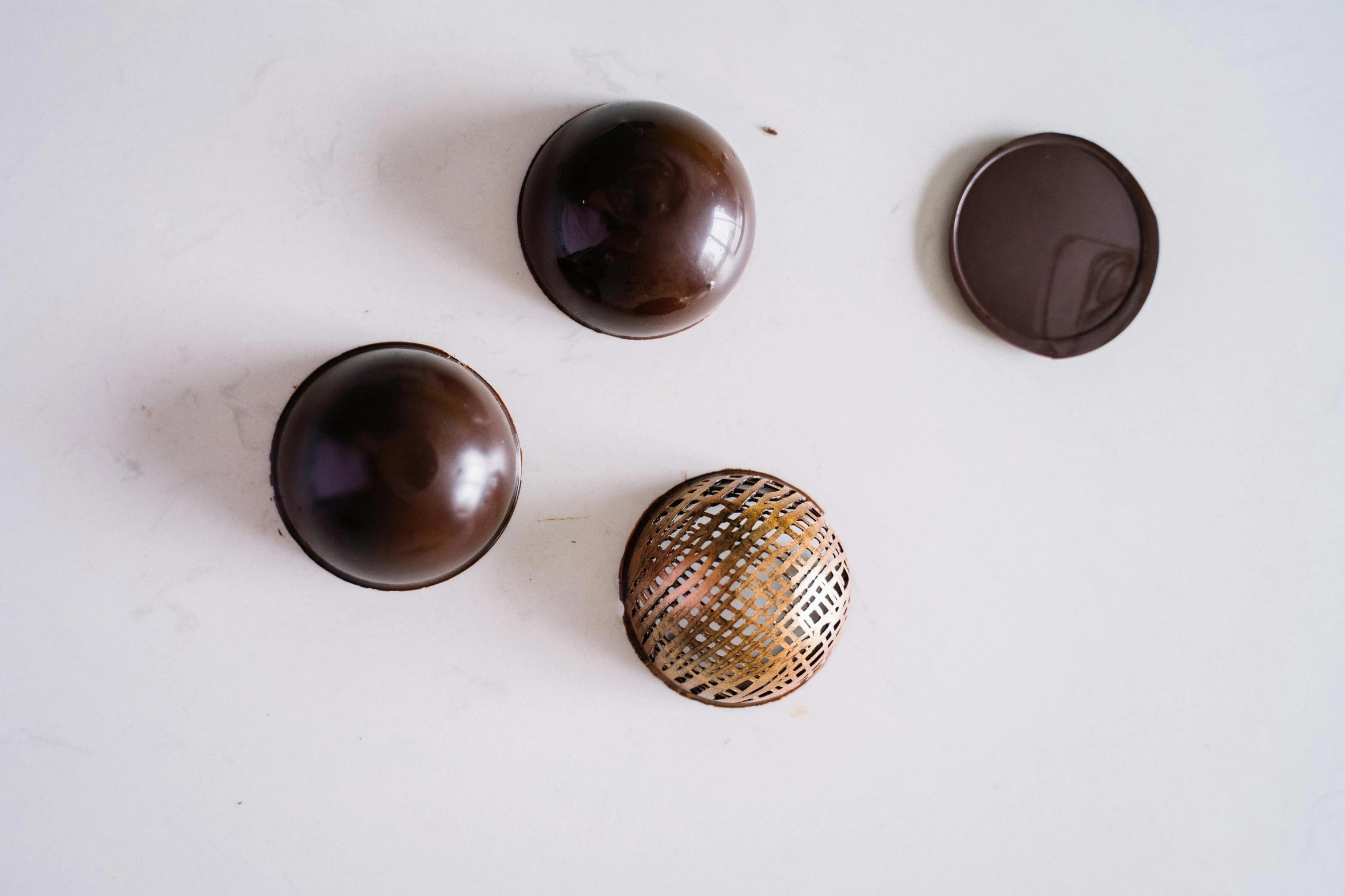 a group of chocolates sitting on top of a white table, a still life, by Julian Hatton, unsplash, assemblage, glossy sphere, metal lid, dark brown, panels