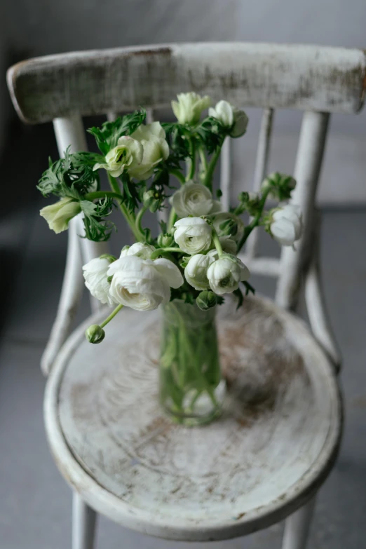 a vase filled with white flowers sitting on a chair, romanticism, light greens and whites, understated, poppy, carefully crafted