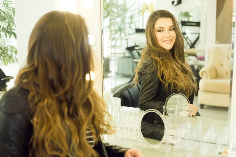 a woman that is sitting in front of a mirror, long brown hair, hairworks, profile image, smiling at camera