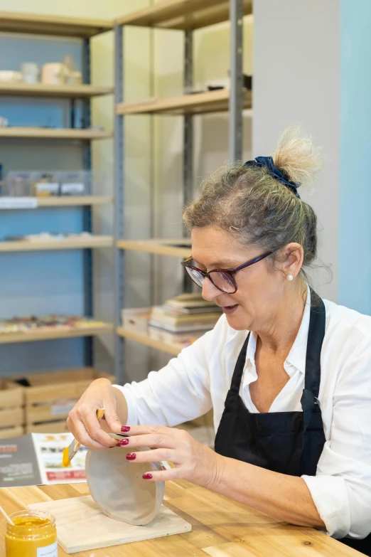 a woman sitting at a table working on a piece of pottery, arbeitsrat für kunst, gourmet and crafts, spanish, resin, profile image