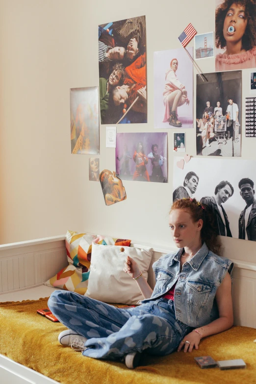 a girl sitting on a bed in a room, poster art, inspired by Nan Goldin, trending on pexels, sadie sink, photos of family on wall, teenager hangout spot, magazine collage