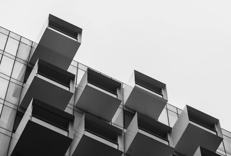 a black and white photo of a building, by Emma Andijewska, unsplash, brutalism, balconies, modular, view from the ground, square shapes