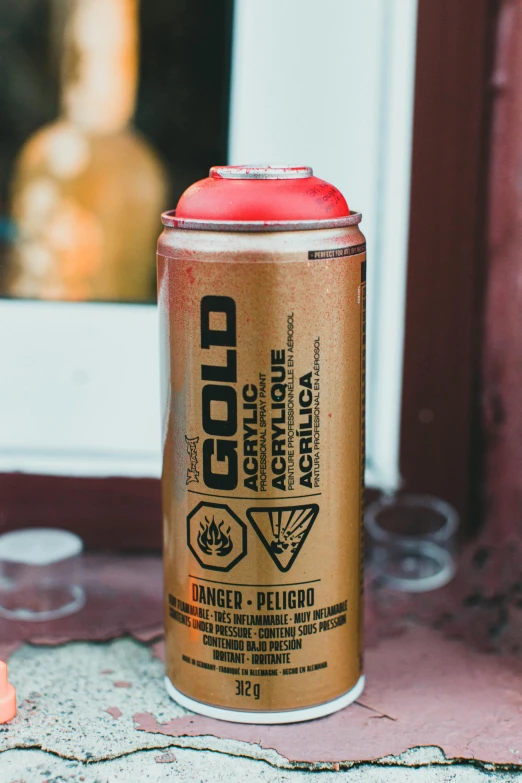 a close up of a spray can on a window sill, by Julia Pishtar, red gold color palette, product label, style blend of burning man, holding gold