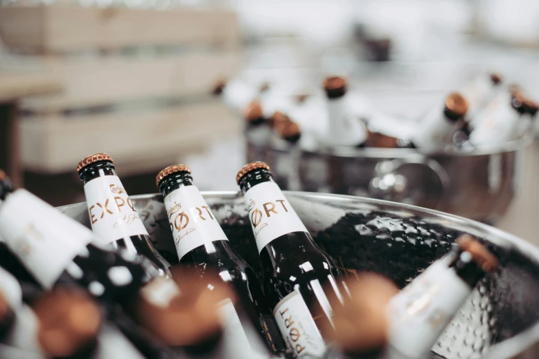 a bunch of bottles of wine in a bucket, by Tuvia Beeri, pexels contest winner, cold beer, extra close-up, beer logo, low dof