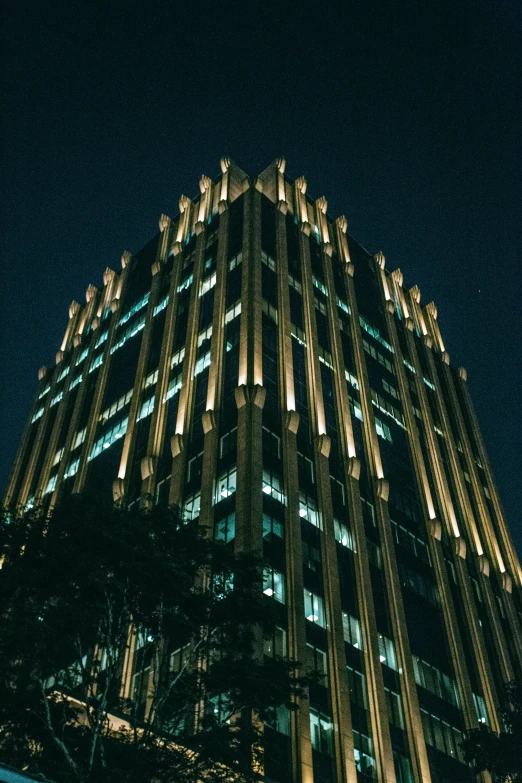 a tall building is lit up at night, inspired by Hugh Ferriss, pexels contest winner, symmetrical details, corporate memphis, downtown mexico, art deco era)