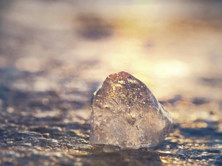 a piece of ice sitting on top of a sandy beach, unsplash, shiny sparkling diamonds, brown, instagram post, unblur