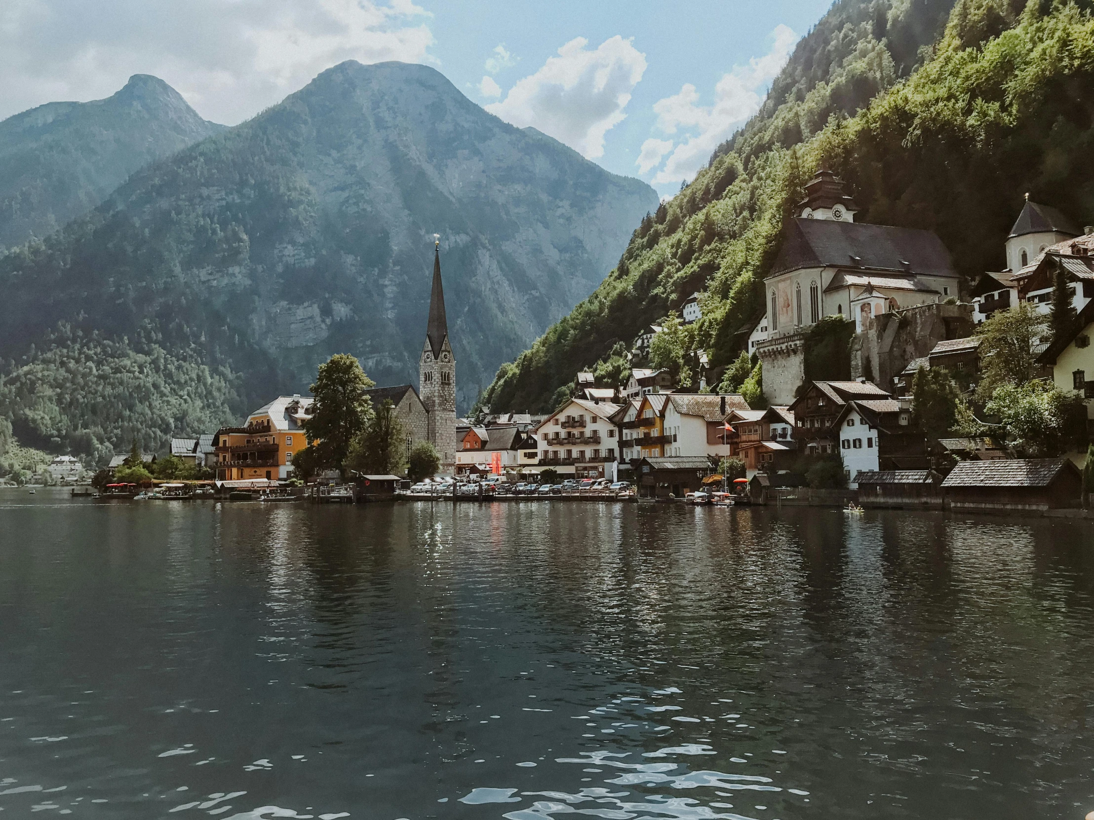 a body of water with houses and mountains in the background, pexels contest winner, austria, ornately dressed, slightly realistic, brown