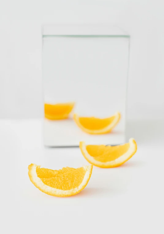 a glass filled with orange slices sitting on top of a table, a picture, postminimalism, looking into a mirror, profile image, at full stride, half turned around