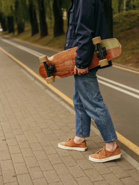 a man standing on the side of a road holding a skateboard, pexels contest winner, renaissance, ( ( ( wearing jeans ) ) ), brown ) ), walnut wood, 15081959 21121991 01012000 4k