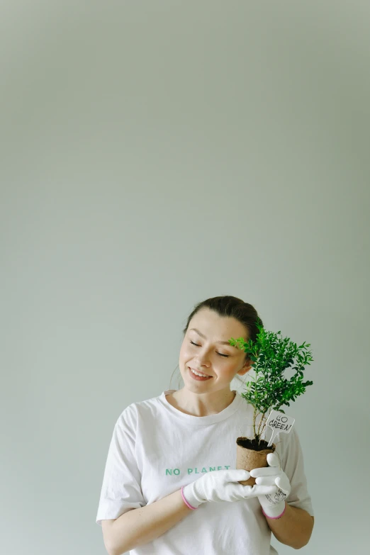 a woman holding a potted plant in her hands, pexels contest winner, minimalism, greta thunberg smiling, portrait image, dressed in a white t-shirt, rex orange county