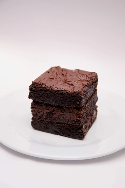 a stack of brownies sitting on top of a white plate, by Emanuel Witz, medium angle, rotated left right front back, with a soft, high quality product photo