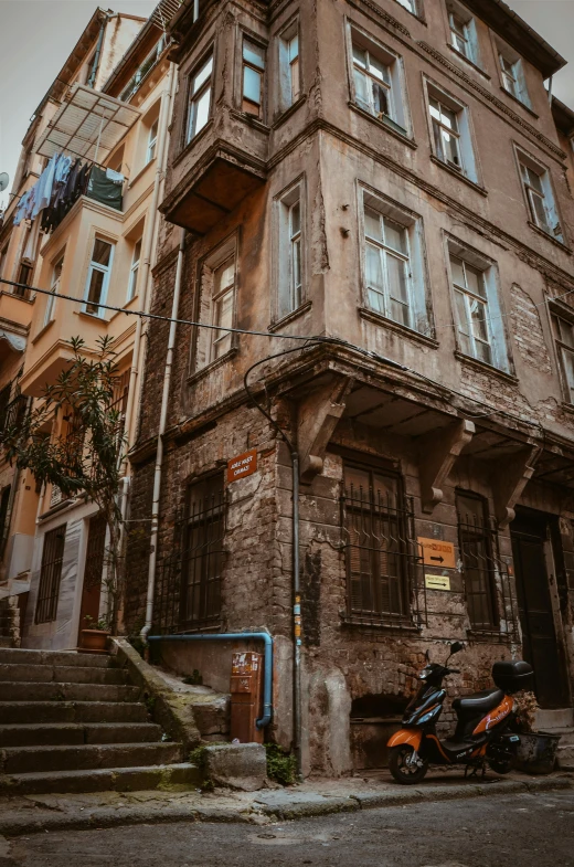 a motorcycle parked in front of a tall building, by Kristian Zahrtmann, pexels contest winner, renaissance, old house, fallout style istanbul, old stone steps, background image