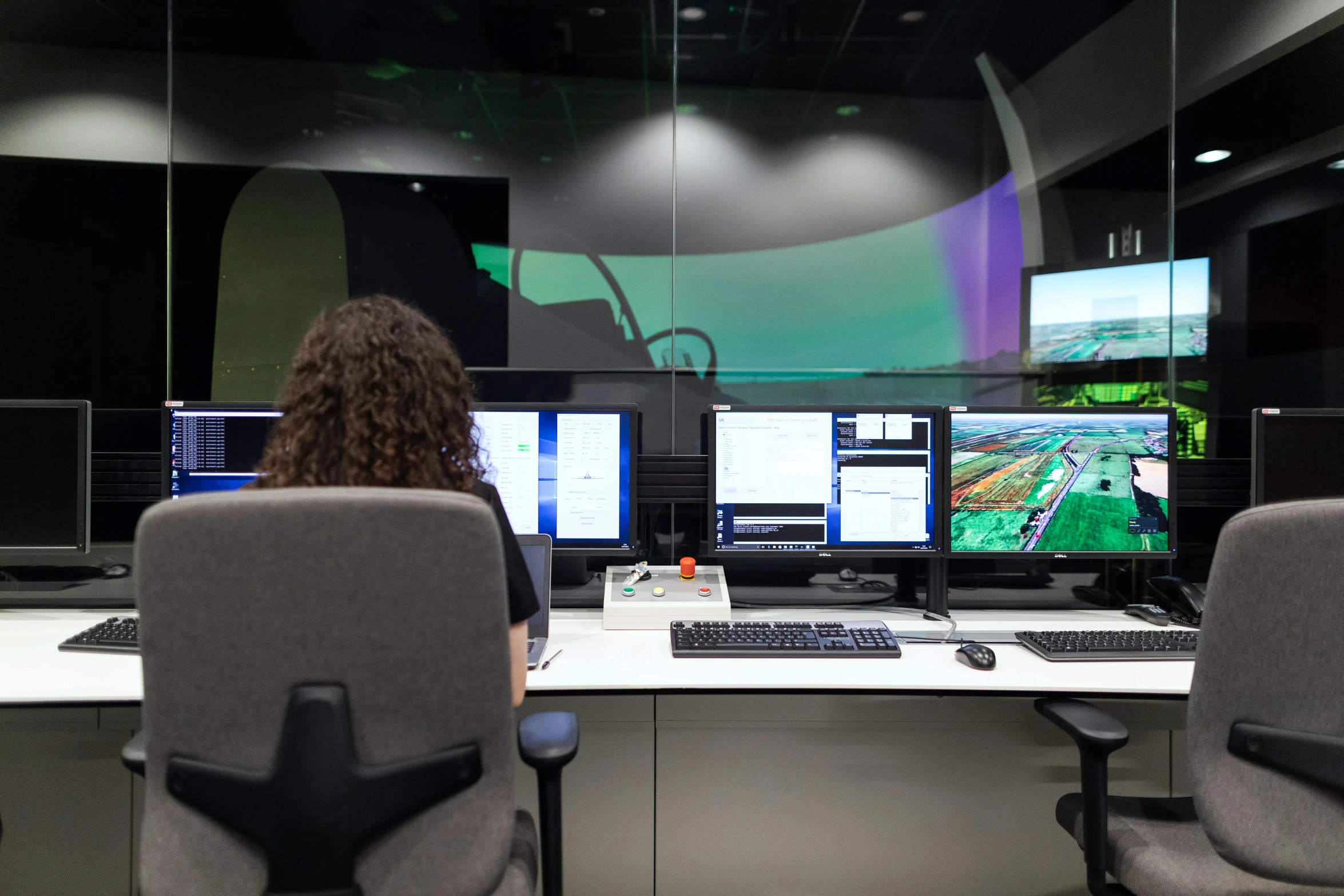 a woman sitting at a desk in front of three monitors, a computer rendering, helicopter view, underground lab, datacentre, unblur