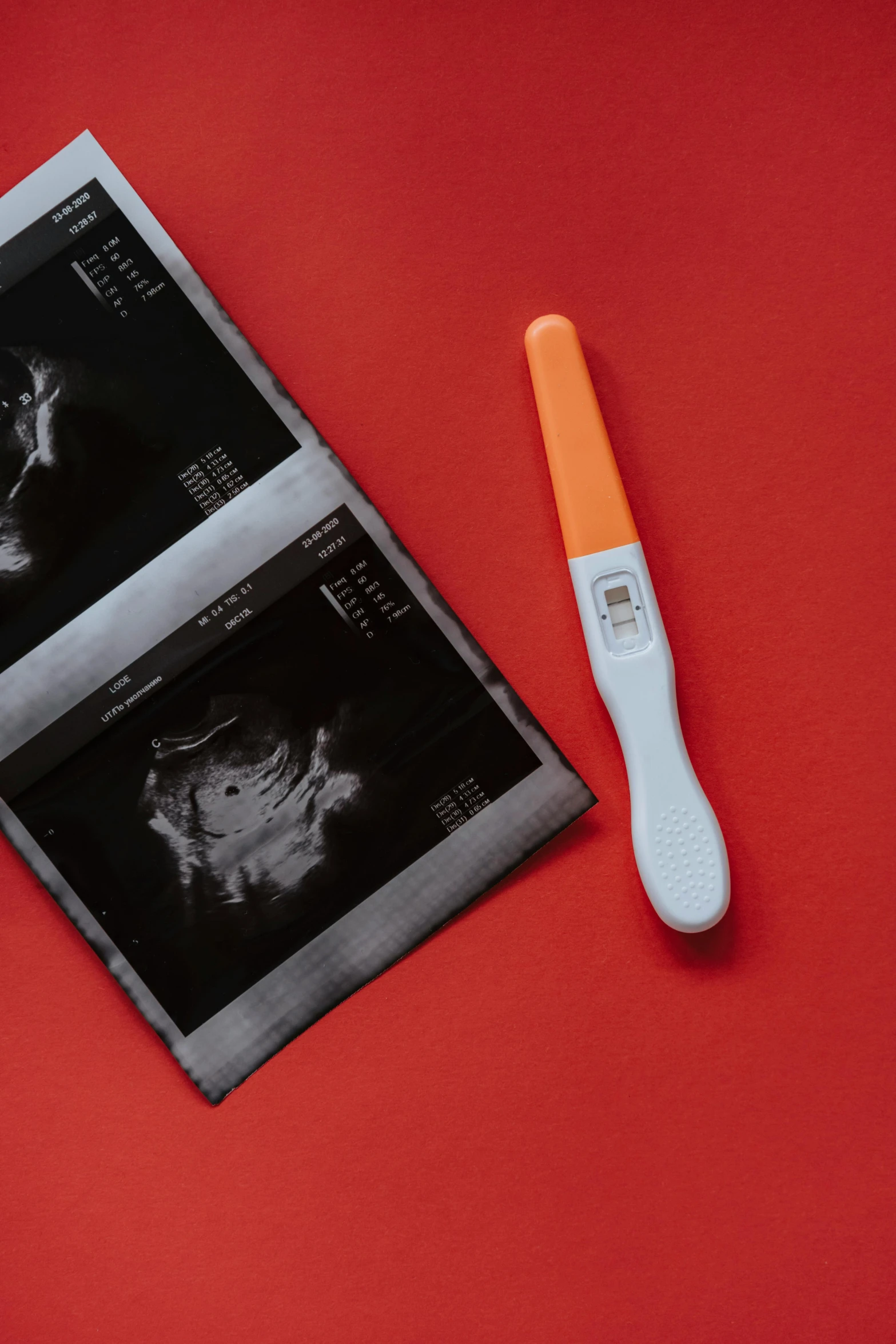 a magazine sitting on top of a red table next to a toothbrush, a black and white photo, pexels contest winner, happening, membrane pregnancy sac, thermography, with a long, on a gray background