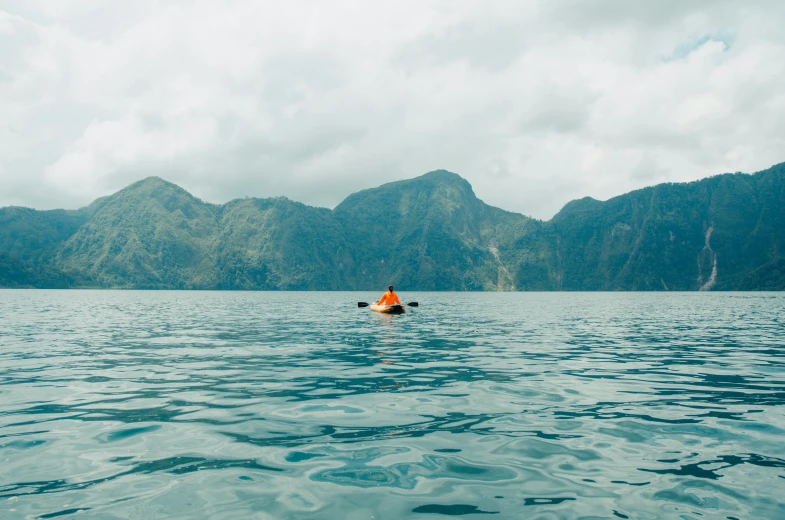 a person in a kayak in the middle of a large body of water, pexels contest winner, philippines, thumbnail, lakeside mountains, alana fletcher