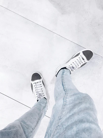 a person standing on top of a white tiled floor, a picture, by Robbie Trevino, trending on unsplash, blue jeans and grey sneakers, instagram filter, white and silver, white background : 3