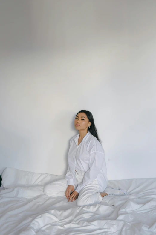 a woman sitting on top of a white bed, inspired by Marina Abramović, pexels contest winner, mai anh tran, charli xcx, wearing simple robes, low quality photo