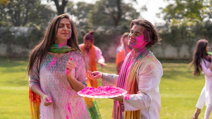a couple of women standing on top of a lush green field, a colorized photo, by Julia Pishtar, pexels contest winner, color field, holi festival of rich color, wearing a silk kurta, guy using the purple fancy suit, promotional image