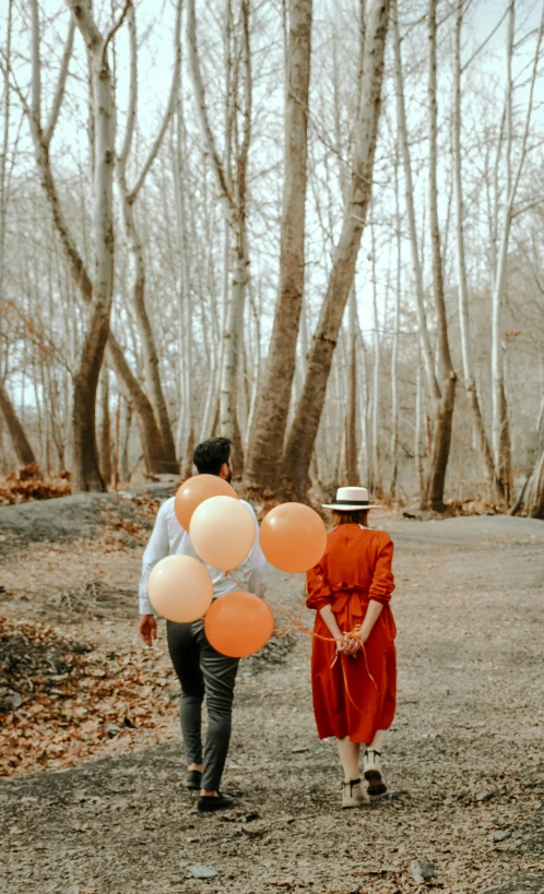 a couple walking down a dirt road holding balloons, by Romain brook, pexels contest winner, orange and white color scheme, forest outside, brown, inspect in inventory image